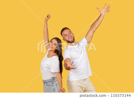 Joyful man and woman in white tops and denim joyously raise their arms 110373144