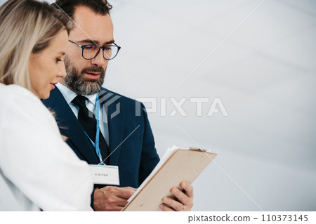 Pharmaceutical sales representative talking with female doctor in medical building. Hospital director consulting with healthcare staff. 110373145