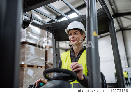 Female warehouse worker driving forklift. Warehouse worker preparing products for shipmennt, delivery, checking stock in warehouse. 110373188