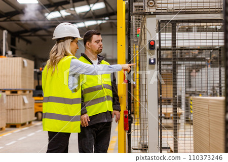 Young man with Down syndrome working in modern factory, manager explaining his job, showing process. Concept of workers with disabilities, support in workplace. Young man with Down syndrome working in modern factory, manager explaining his job, showing process. Concept of workers with disabilities, support in workplace. 110373246
