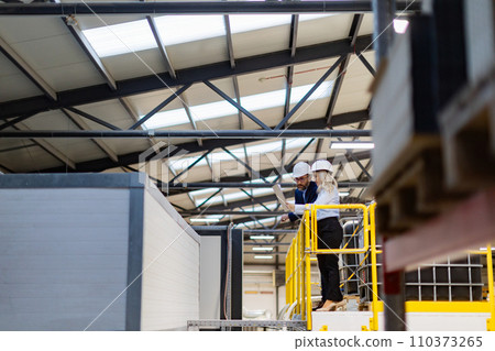 Female engineer and male project manager standing in modern industrial factory, talking about production. Team management in manufacturing facility 110373265
