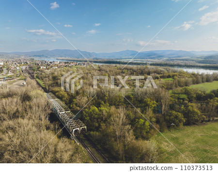 Aerial view of big metal railway bridge in Slovakia, in the middle of summer forest. 110373513