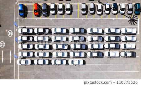 Aerial view of a parking lot at a car manufacturing facility with newly produced vehicles parked in rows. 110373526