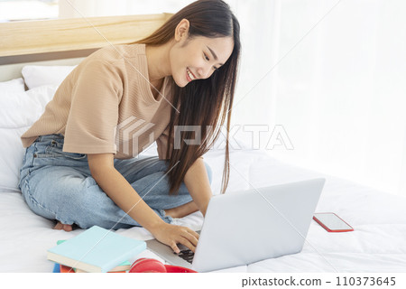 Happiness Asian Woman working from home using laptop online meeting in home office. Happy relax time asian business woman typing keyboard use notebook laptop Smiling, laughing at home office. Happiness Asian Woman working from home using laptop online meeting in home office. Happy relax time asian business woman typing keyboard use notebook laptop Smiling, laughing at home office. 110373645