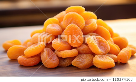 A pile of dried apricots lies on a wooden table A pile of dried apricots lies on a wooden table 110374103