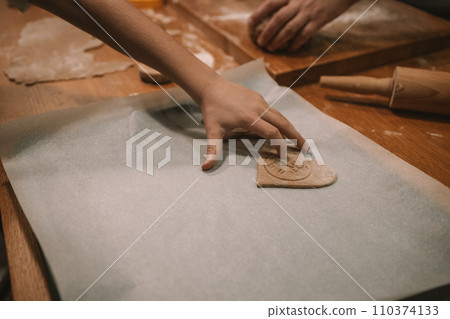 Process of making heart-shaped gingerbread for Christmas and New Year. Traditional festive food making, family culinary.  110374133