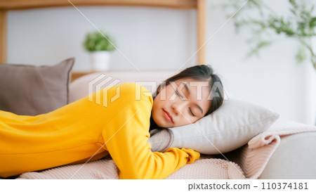 Asian woman resting at home on couch, feeling exhausted after work Asian woman resting at home on couch, feeling exhausted after work 110374181