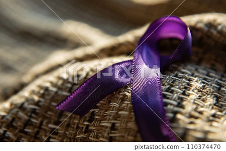 A close-up of a purple ribbon, the symbol of overdose awareness, pinned to a fabric with subtle textures 110374470