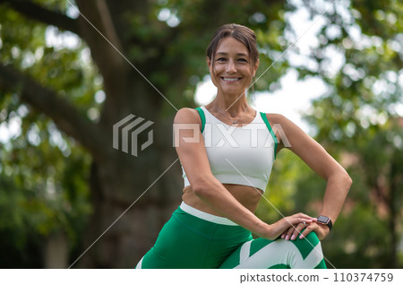 Woman in green sportswear exercising in the park Woman in green sportswear exercising in the park 110374759