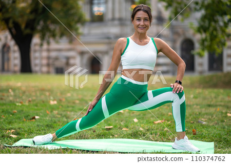 Woman in green leggings doing lunges on the lawn Woman in green leggings doing lunges on the lawn 110374762
