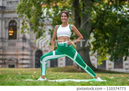 Woman in green leggings doing lunges on the lawn Woman in green leggings doing lunges on the lawn 110374773