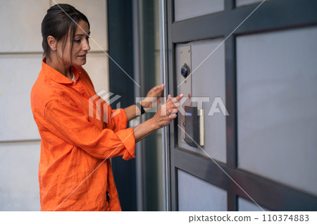 Woman employs advanced electronic technology to ensure the security of her house. 110374883