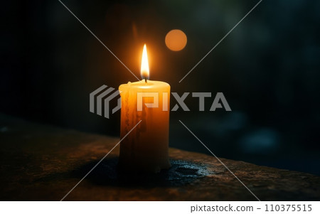 A single candle burning brightly in a dark room, casting a gentle glow. The candle symbolizes remembrance and awareness 110375515