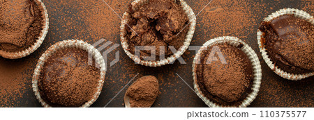 Chocolate browny muffins and cocoa in teaspoon top view on brown rustic stone background, sweet homemade dark chocolate cupcakes 110375577