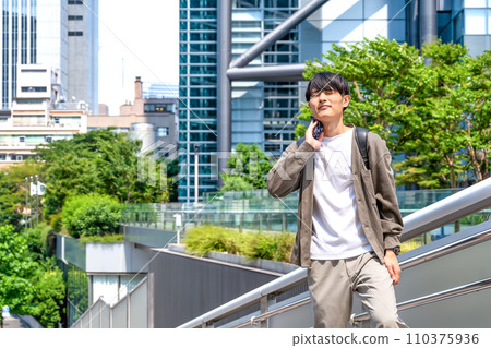 A young business man in office casual clothes, in front of Shimbashi Station, wiping his sweat A young business man in office casual clothes, in front of Shimbashi Station, wiping his sweat 110375936