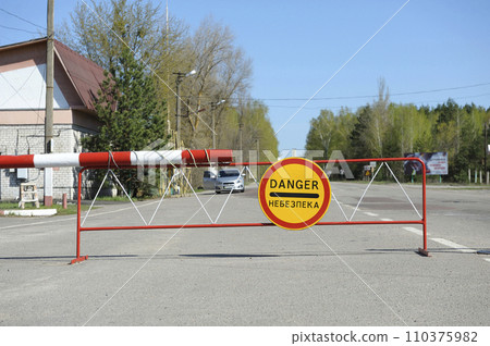 Sign Danger on a barrier, crossing point Dytiatky where Chornobyl Exclusion Zone begins. 110375982