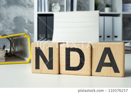 Office desk with wooden cubes NDA Non-Disclosure Agreement. 110376257