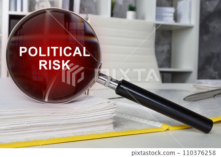 A folder with documents and a magnifying glass with the inscription political risk. A folder with documents and a magnifying glass with the inscription political risk. 110376258
