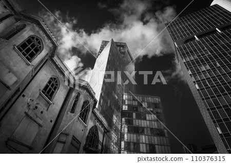 Striking black and white image capturing the stark contrast between a dilapidated old building and a towering modern skyscraper against a dramatic sky in Tel Aviv, Israel Striking black and white image capturing the stark contrast between a dilapidated old building and a towering modern skyscraper against a dramatic sky in Tel Aviv, Israel 110376315