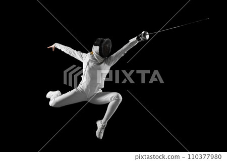 Artistry of combat. Female fencer gracefully executes complex fencing maneuver in action against black studio background. Concept of combat sport. Artistry of combat. Female fencer gracefully executes complex fencing maneuver in action against black studio background. Concept of combat sport. 110377980