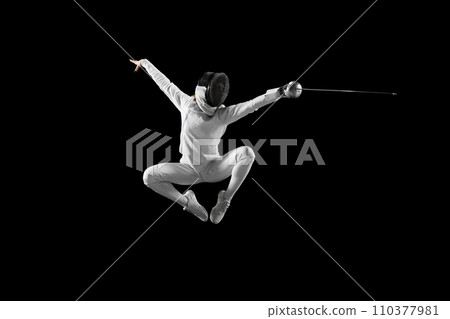 Dynamic mid-air snapshot of swift motion of female fencer's blade, dynamic lines and angles of her body during fight against black studio background. 110377981