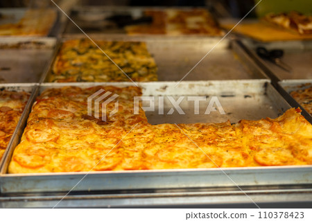 Authentic Italian pizza in a restaurant display window. Various pizzeria in glass window display. Focus on pizza with tomatoes Authentic Italian pizza in a restaurant display window. Various pizzeria in glass window display. Focus on pizza with tomatoes 110378423