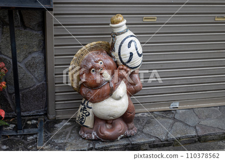 A cute ceramic raccoon figurine placed in front of the store A cute ceramic raccoon figurine placed in front of the store 110378562