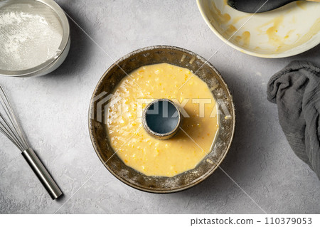 Cooking orange bundt cake. Top view uncooked orange bundt cake in baking pan. 110379053