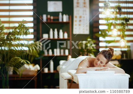relaxed modern female in spa salon laying on massage table relaxed modern female in spa salon laying on massage table 110380789