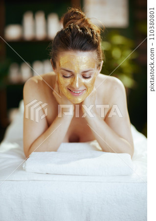 happy modern female in spa salon laying on massage table 110380801