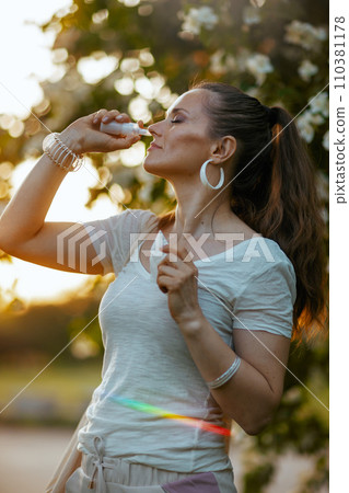 trendy woman in white shirt using nasal spray 110381178