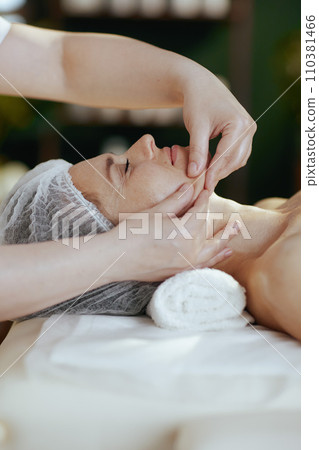 medical massage therapist massaging clients face 110381466