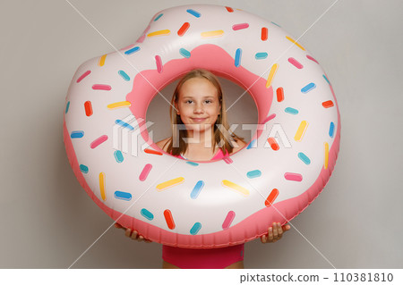 Summer young girl in pink swimsuit holding inflatable swimming pool ring donut.  110381810
