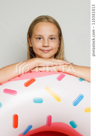 Cheerful happy child girl with inflatable ring swimming float closeup. 110381813