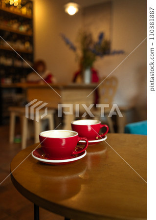 Close-up of two red cups of coffee on wooden rustic background with beautiful latte art Close-up of two red cups of coffee on wooden rustic background with beautiful latte art 110381887