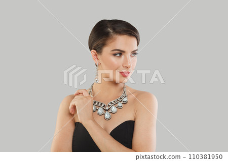 Cheerful jewelry model woman with dark brown hair and shiny fresh skin wearing diamond earring 110381950