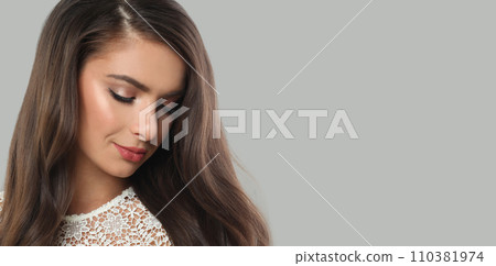 Cute woman brunette with long dark healthy wavy hair and makeup  on gray background.  110381974