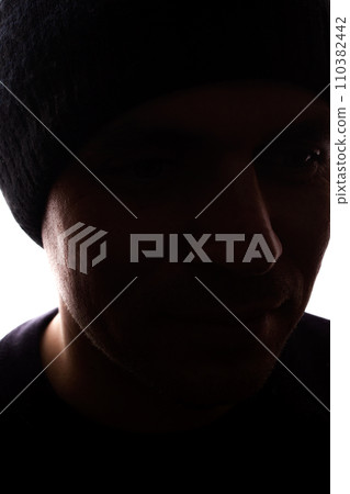 Portrait young man, unshaven, side view in cap - dark silhouette 110382442