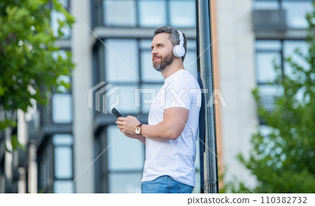 man choose music playlist in the street. man choosing music playlist outside. 110382732