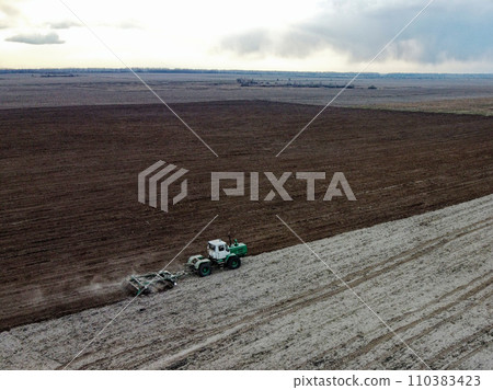 Tractor plows a field, aerial view. Agricultural landscape. Tractor plows a field, aerial view. Agricultural landscape. 110383423
