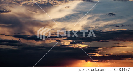 The sky filled with dark clouds and a shining sun at sunset. 110383457