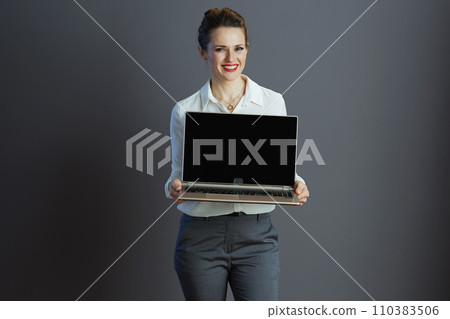 happy female employee showing laptop blank screen against gray 110383506