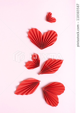 Beautiful composition of folded red paper hearts and leaves on a pink background  vertical view 110383587