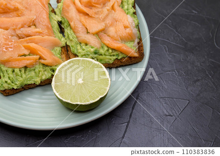 Whole grain bread with avocado paste, lime, salmon on a marble surface 110383836