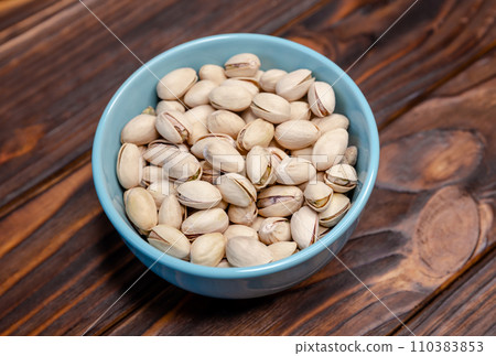 Salted roasted pistachios nuts with shell on wooden background Salted roasted pistachios nuts with shell on wooden background 110383853