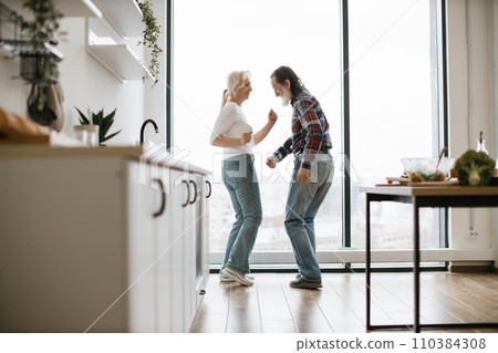 Elderly pensioners blond wife and husband with gray beard listening to music and dancing twist 110384308