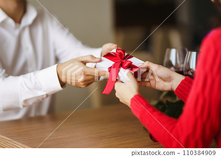 Man gives to his woman a gift box with red ribbon. Hands of man gives surprise gift box for girl. Man gives to his woman a gift box with red ribbon. Hands of man gives surprise gift box for girl. 110384909