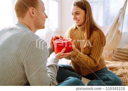 Valentine's Day concept. Exchange of gifts. Young couple at home celebrating Valentine's Day. Valentine's Day concept. Exchange of gifts. Young couple at home celebrating Valentine's Day. 110385228