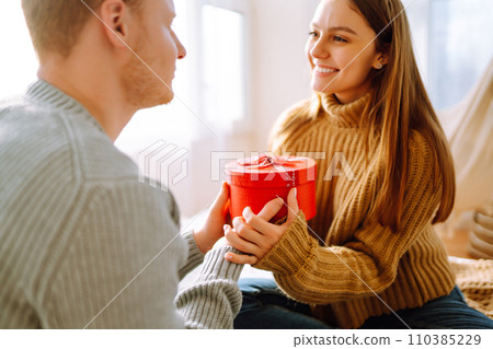 Valentine's Day concept. Exchange of gifts. Young couple at home celebrating Valentine's Day. Valentine's Day concept. Exchange of gifts. Young couple at home celebrating Valentine's Day. 110385229