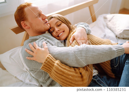 Couple in love relaxing at home on bed while they hug each other. Valentine's Day, holiday concept. Couple in love relaxing at home on bed while they hug each other. Valentine's Day, holiday concept. 110385231